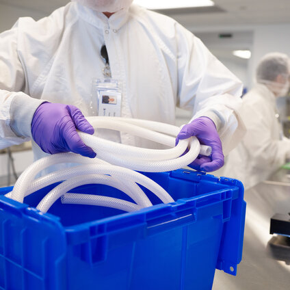 Technician in a cleanroom handling flexible bioprocessing tubing during laboratory assembly.