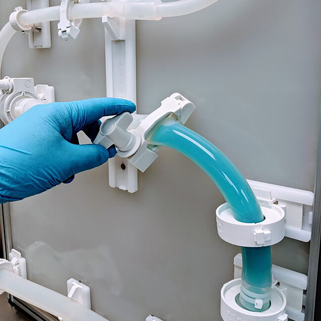 Hand connecting single‑use bioprocessing tubing in a controlled laboratory tubing management system.