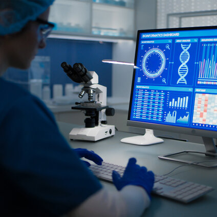 Laboratory workstation displaying a bioinformatics dashboard with genomic data visualizations and analytical charts.
