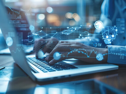 Hands typing on a laptop with overlaid digital data analytics and AI visualization graphics.
