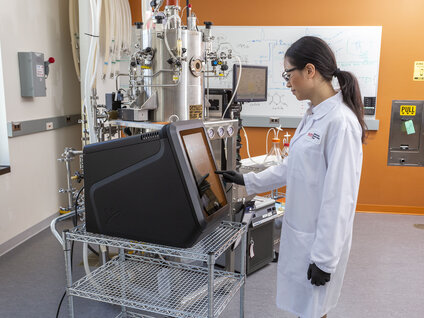 Laboratory operator using a process modeling system to analyze cell culture media connected to a bioreactor.