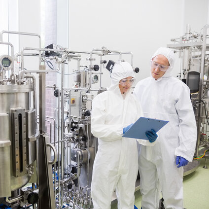 Bioprocessing operators reviewing real‑time data from an inline FlowVPX process analytics system during downstream biopharmaceutical development and manufacturing.